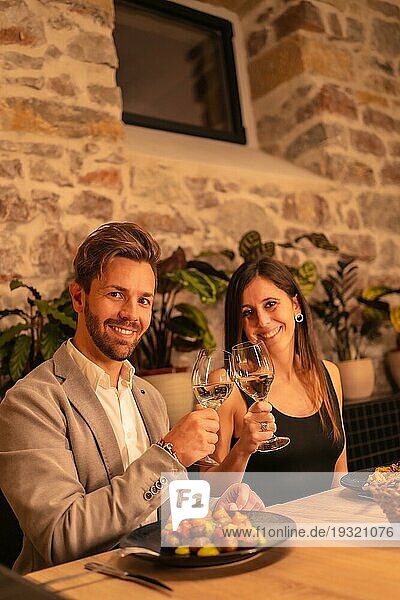 Lifestyle  ein hübsches  verliebtes junges Paar in einem Restaurant  das mit einem Glas Wein anstößt  um den Valentinstag zu feiern  vertikales Foto