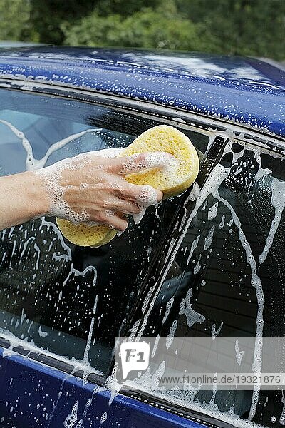 Mann wäscht Auto mit einem seifigen Schwamm