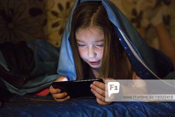 Mädchen spielt Smartphone Spiel dunklen Raum