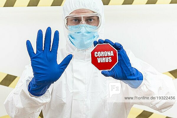 Mann im Schutzanzug mit Coronavirus Stoppschild