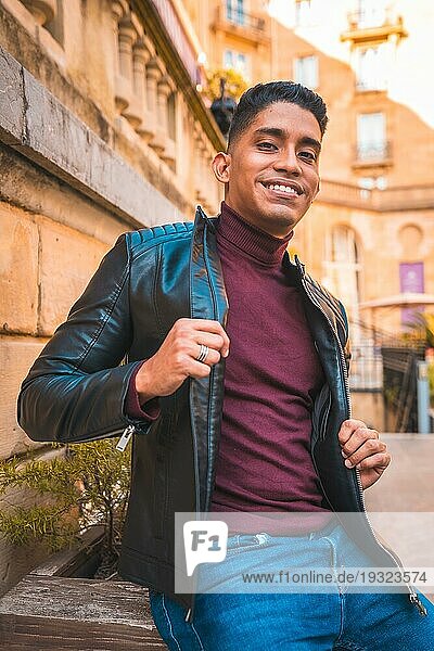 ModeLifestyle Porträt eines Latino Jungen in der Stadt. Jeans  Lederjacke und braune Schuhe