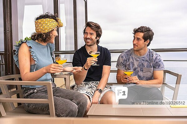 Drei entspannte Freunde  die ihren Urlaub mit Cocktails auf einer Terrasse feiern