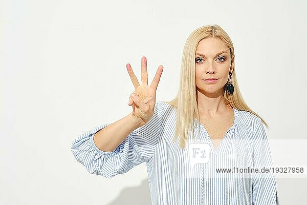 Attraktive blonde Frau zeigt drei Finger. Zählen mit Fingern