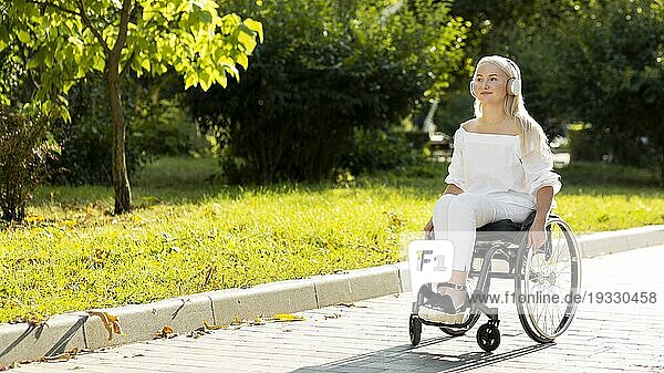 Frau im Rollstuhl hört Musik im Freien