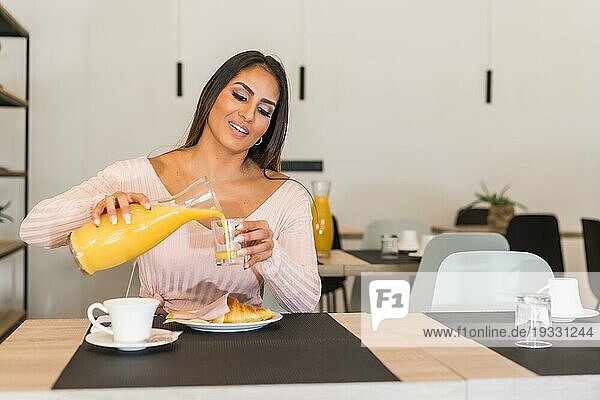 Horizontales Porträt einer lässigen Geschäftsfrau  die beim Frühstück in einem Hotel Orangensaft trinkt