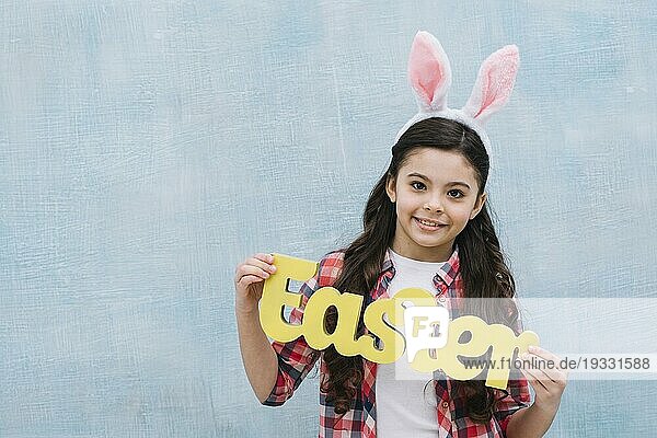 Lächelnde Porträt Mädchen hält gelbe Ostern Wort suchen Kamera