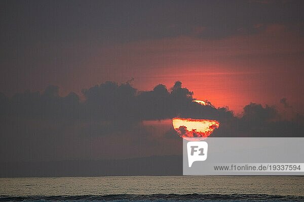 Sonnenaufgang am Sandstrand. Landschaftsaufnahme mit roter kreisförmiger Sonne am Strand von Sanur  Bali  Indonesien  Asien