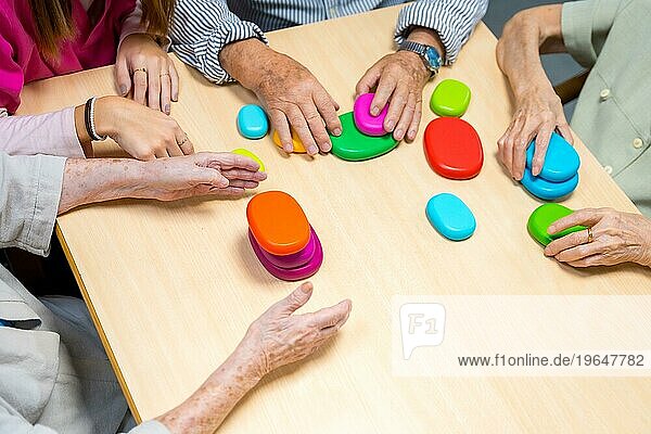 Draufsicht auf die Hände von alten Menschen  die in einem Pflegeheim ein Brettspiel spielen