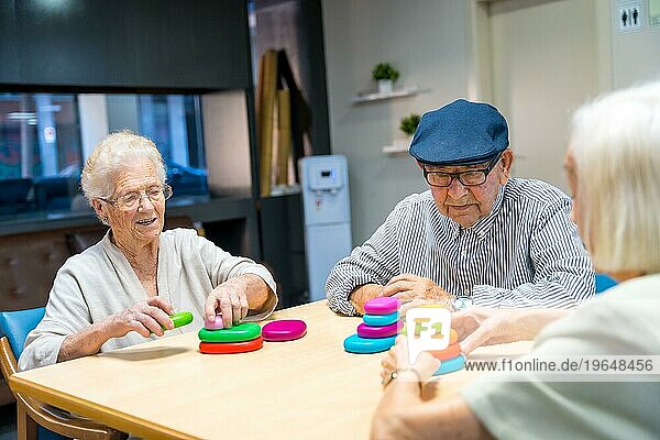 Drei niedliche ältere Menschen  die zusammen in einem Pflegeheim Geschicklichkeitsspiele spielen