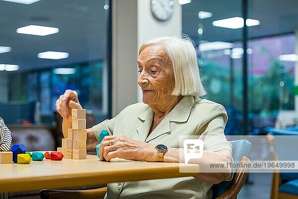 Porträt einer fröhlichen  netten älteren Frau in einem Pflegeheim  die Geschicklichkeitsspiele spielt