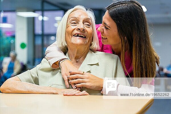 Glückliche ältere Frau und Krankenschwester umarmt in einem Pflegeheim
