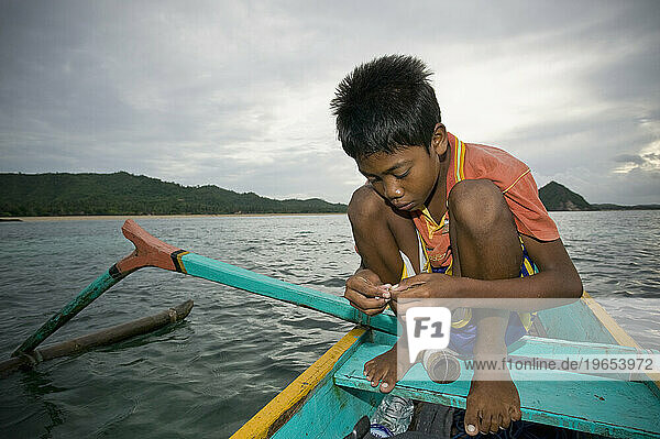 A young boy prepares his line for fishing in Kuta  Lombok  Indonesia.