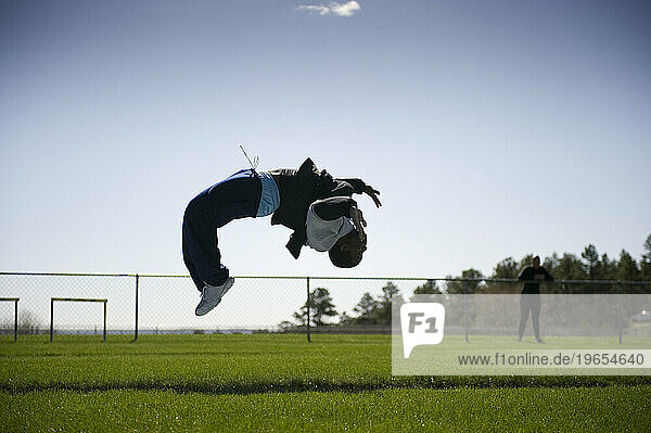 An athlete does backflips after completing the mile run during track practice.