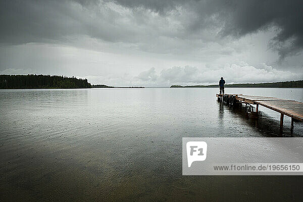 A man stands on the pier on Gregoire Lake.