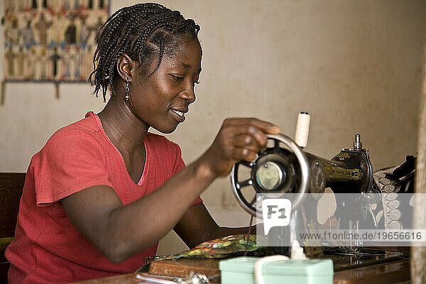 Young Liberian woman learning how to sew