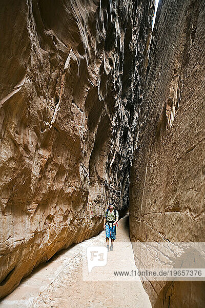 man hiking down narrow desert slot canyon  Robbers Roost  Utah