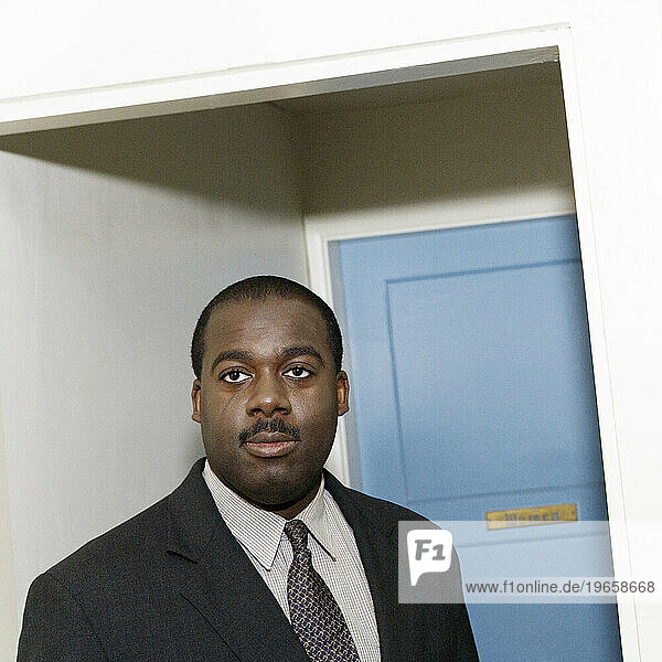 Portrait of an African American man standing in a hallway.