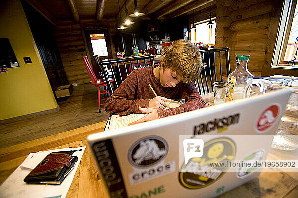 Young male kayaker doing homework in his kitchen.