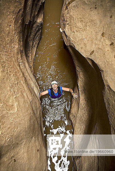 A woman wades though water in a desert slot canyon in Utah.