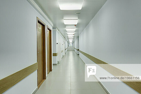Brightly lit corridor in a sports hall with doors leading off it.