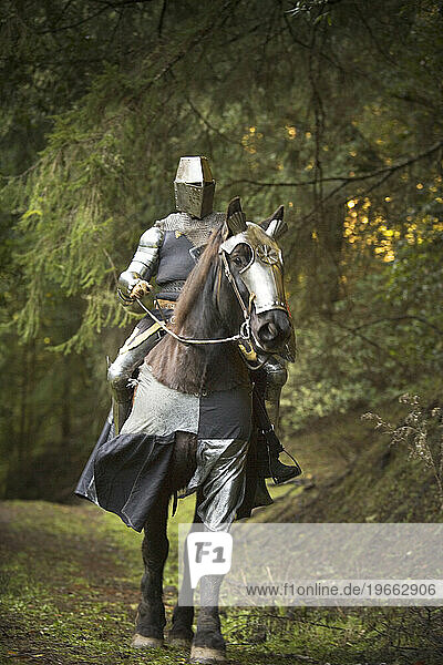 Man on horseback dressed as medieval warrior.