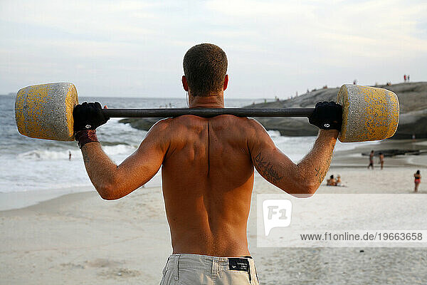 Man training at a public outdoors gym on Arpoador beach  Rio de Janeiro  Brazil.