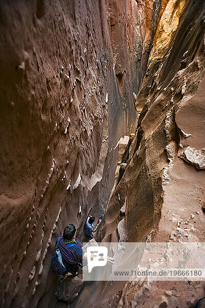 Three people descending a slot canyon  Utah.