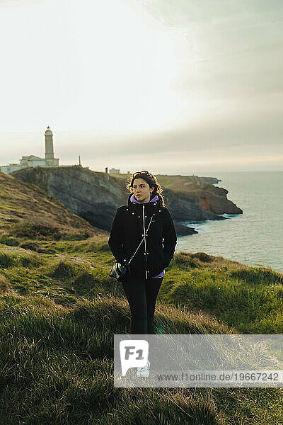 Portrait of a girl on a cliff with a lighthouse in the background