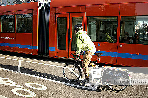 Bike commuter on an extracycle riding next to the street car.