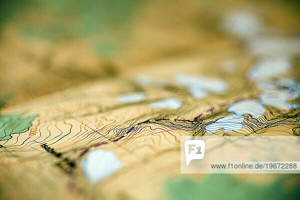 Detail view of a paper map showing topographic contours of mountains and glaciers.