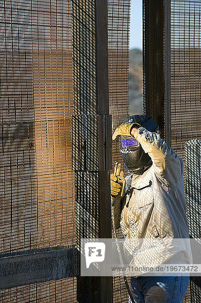 Welder repairs the pedestrian border fence with Mexico  AZ.