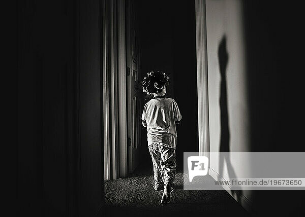 Young child walking down dark hallway wearing curlers