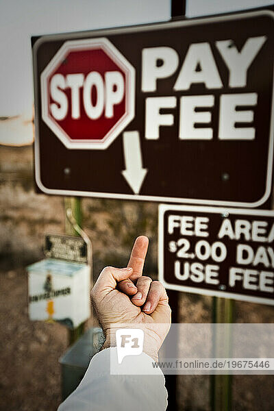 Person's arm extended flipping off a fee sign  Utah.