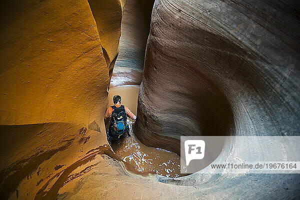 A man wading in water in sculpted slot canyon  Utah.