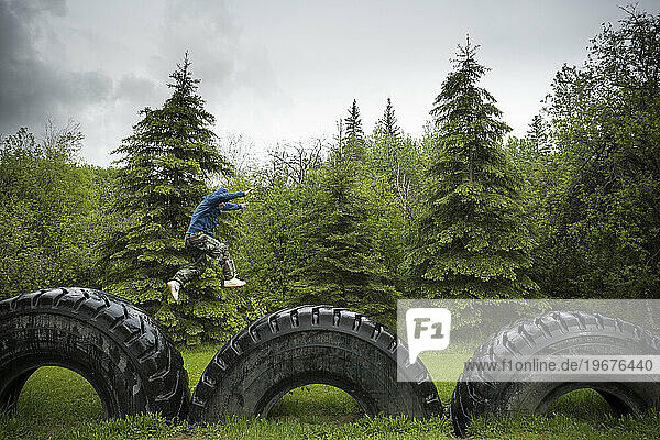 A young man from Anzac  Alberta  jumps from giant tire to giant tire  signals of the industrial development in the region.