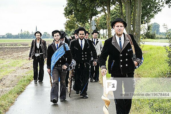 Eine Gruppe von Rolandsbrüdern begleitet einen Wandergesellen zu seiner Einheimischmeldung in Großniedesheim