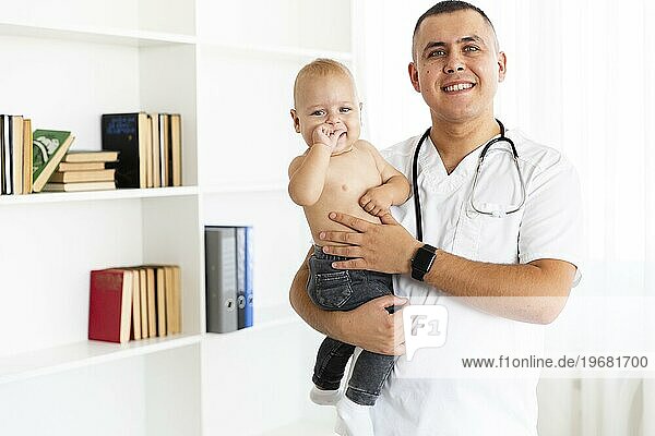 Lächelnder Arzt  der ein entzückendes kleines Baby hält
