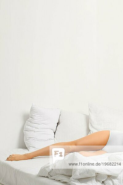 Abgeschnittenes Bild eines schlanken Frauenbeins im Bett