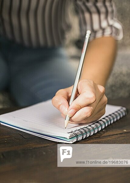Frau schreibt mit Bleistift Spirale Notizbuch Holztisch