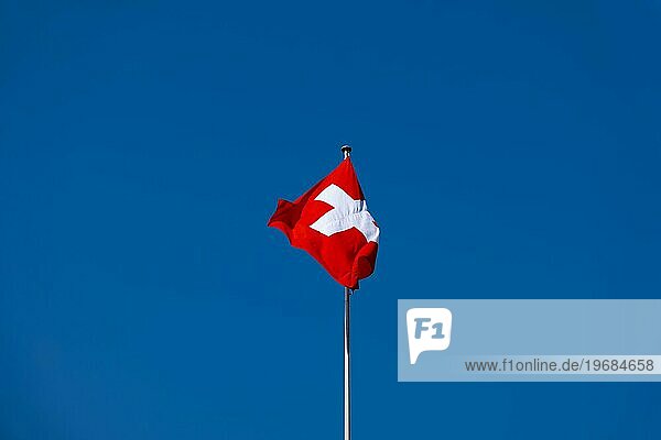 Schöne Schweizer Flagge gegen blauen klaren Himmel in einem sonnigen und windigen Tag in der Schweiz
