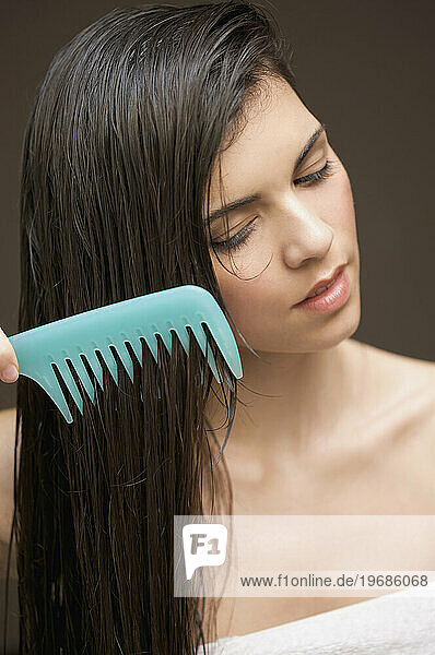 Woman combing her hair with a wide tooth comb