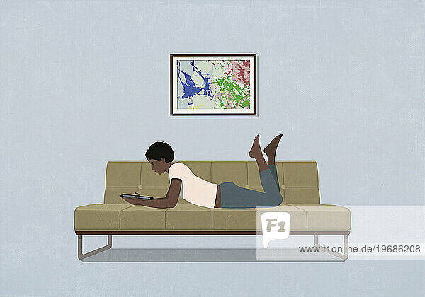 Woman laying and relaxing  using digital tablet on living room sofa at home