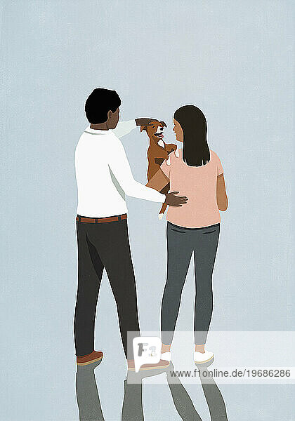 Couple holding and petting cute puppy dog on blue background