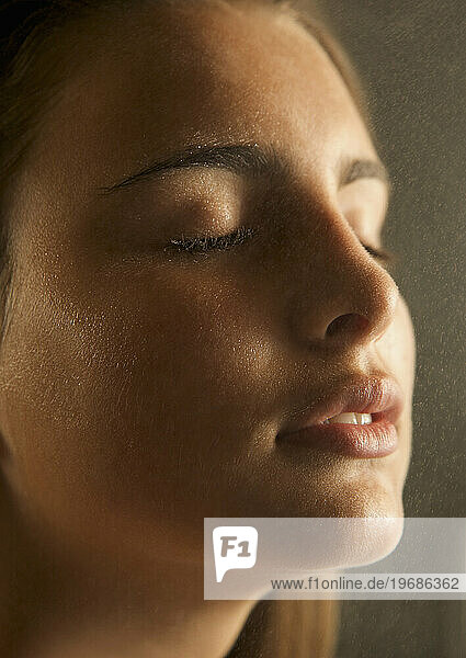 Close up of a young woman face covered in misty water