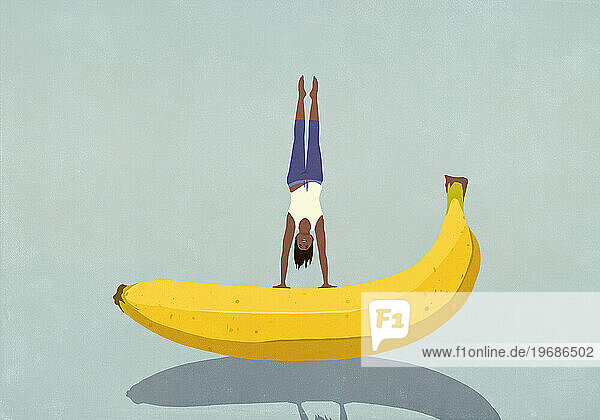 Healthy woman balancing upside-down on banana