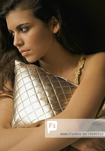 Woman hugging a gold quilted cushion