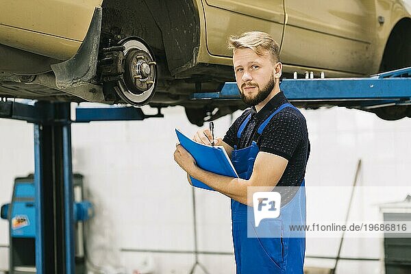 Handsome technician working car workshop