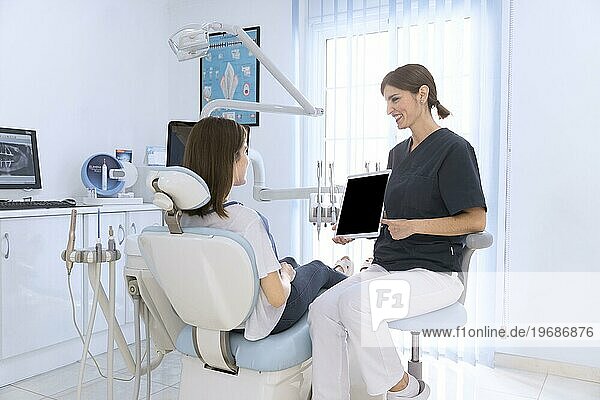 Zahnarzt zeigt digitales Tablet weiblichen Patienten Klinik