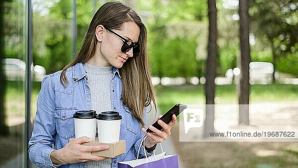 Schöne Frau mit Kaffee in der Hand  während sie ihr Telefon überprüft