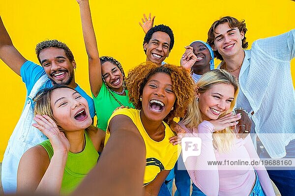 Frontalansicht von glücklichen diversen Freunden  die ein Selfie machen  lächelnd und lachend vor einem gelben Hintergrund